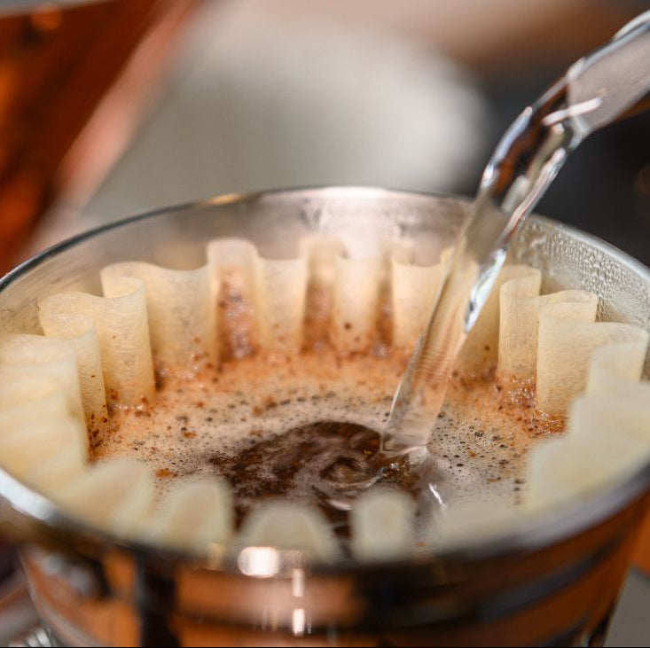 Coffee being poured into a coffee filter with a blurred background