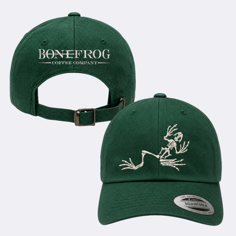 A dark green baseball cap shown from both front and back angles. The front features an embroidered white skeleton frog, and the back displays 'BONEFROG COFFEE COMPANY' in white text with a matching green strap and metal buckle.